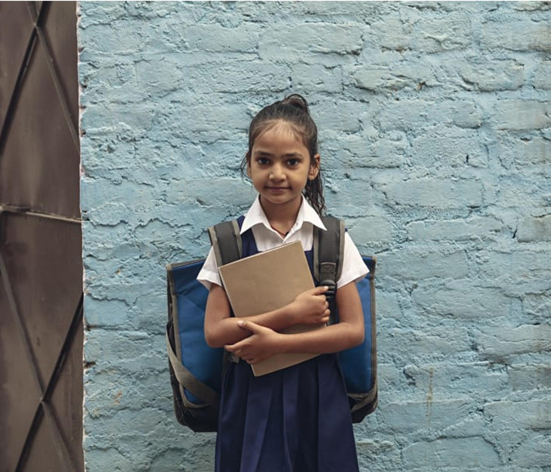 A girl in a uniform with a bag and a book.